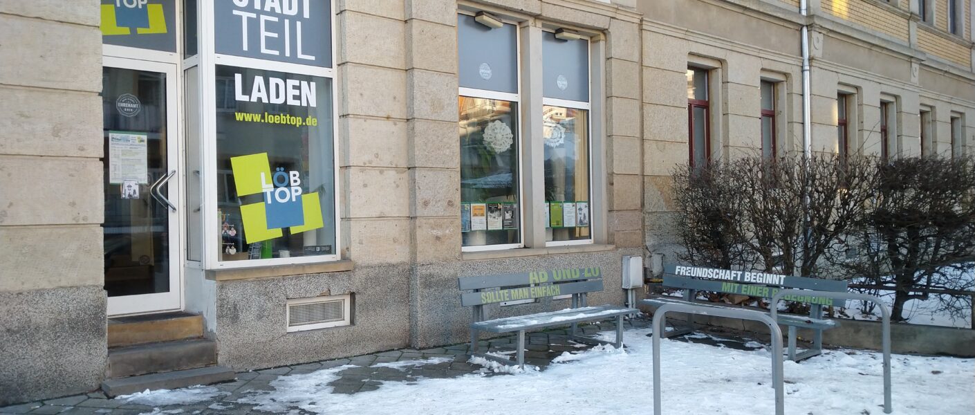 Ladenlokal von außen mit Fahrradständer und zwei Sitzbänken. Es liegt Schnee und der Stadtteilladen hat geschlossen.