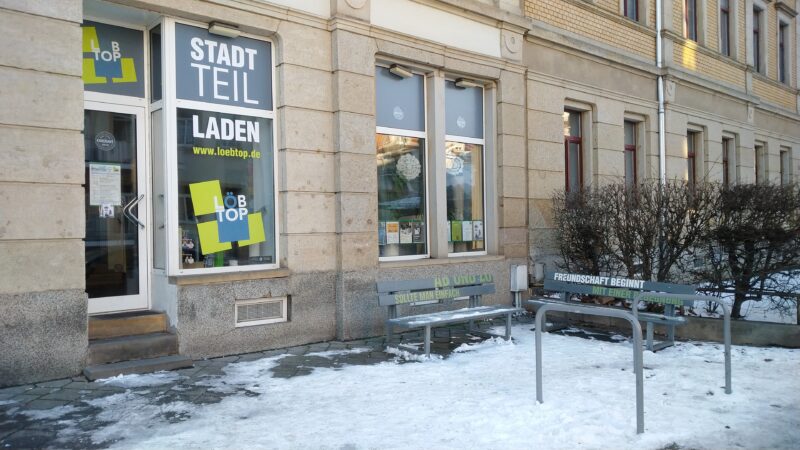 Ladenlokal von außen mit Fahrradständer und zwei Sitzbänken. Es liegt Schnee und der Stadtteilladen hat geschlossen.