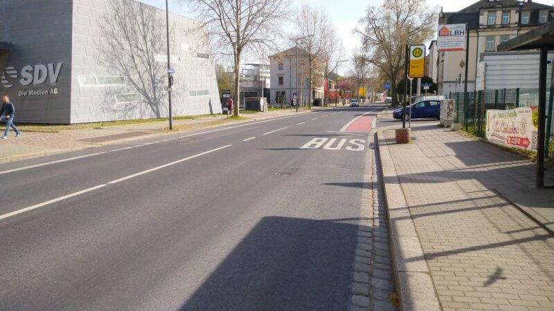 Tharandter Straße mit zwei Fahrspuren und Fahrrad-Angebotsstreifen, teils rot markiert. Im vorderen Bereich eine Bushaltestelle. Von rechts mündet die Clara-Viebig-Straße ein. Es gibt keine Fußgängerquerung.