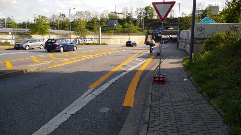 Straße mit vielen gelben Markierungen, ein Radfahrer, wenig Autos