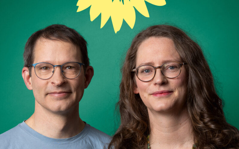Wahlplakat mit zwei Menschen. Links Alexander Bigga, rechts Susanne Krause. Darüber eine halbe, gelbe Sonnenblume vor dunkelgrünem Hintergrund. Slogan: Gutes Klima im Stadtteil.