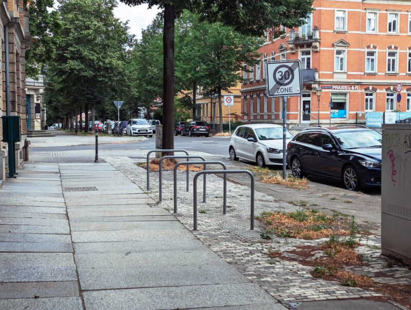 Vier Fahrradbügel auf dem Fußweg an der Kreuzung Clara-Zetkin-Straße / Bünaustraße. Es ist kein Fahrrad angeschlossen.