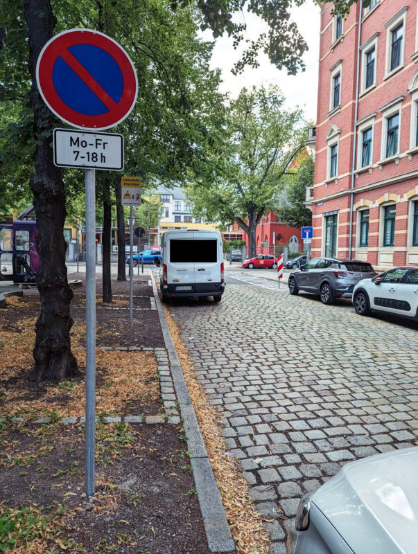 Ein Parkverbotsschild im Vordergrund mit dem Zusatz "Mo-Fr 7-18 Uhr". Dahinter ein Schild mit dem Text "Haltestelle Elterntaxi".